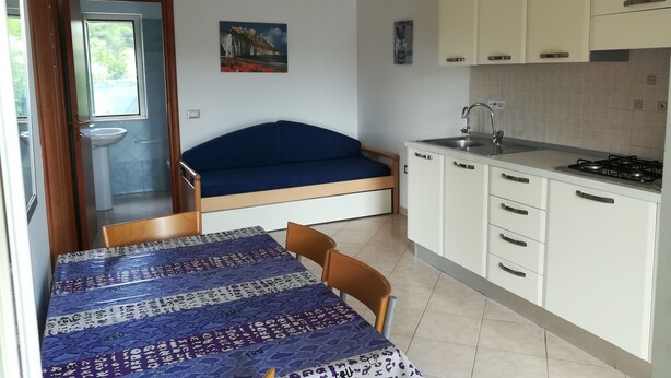 A compact room with a bed, a small kitchenette, a sink, and a window. - Holidays in Vieste in Charming Villas - 1 (Vieste)