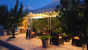 An outdoor seating area with tables and chairs, surrounded by potted plants and trees. - Holidays in Vieste in Charming Villas - 1 (Vieste)