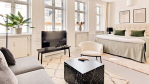 A modern living room with a sofa, a coffee table, a TV, and a bed with a headboard. - City 2- Cosy 1 Bdr Apt In the Center of Copenhagen (Copenhagen)
