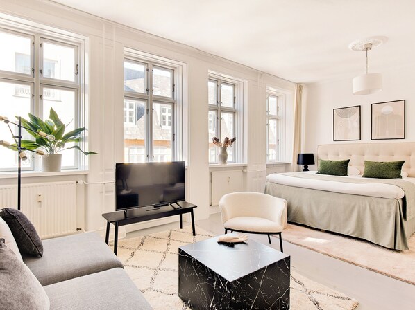 A modern living room with a sofa, a coffee table, a TV, and a bed with a headboard. - City 2- Cosy 1 Bdr Apt In the Center of Copenhagen (Copenhagen)