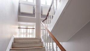 A staircase with white balusters and a wooden handrail leading to a landing with a door and windows. - City 2- Cosy 1 Bdr Apt In the Center of Copenhagen (Copenhagen)
