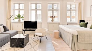 A modern hotel room with a sofa, a TV, a bed, and large windows. - City 2- Cosy 1 Bdr Apt In the Center of Copenhagen (Copenhagen)
