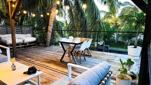 A wooden deck with a table and chairs, surrounded by palm trees and a view of the garden. - Ti Bout Paradi Ti Zil (Tamarin)