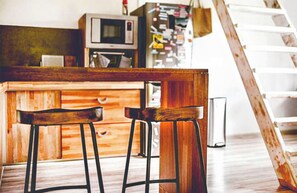 A wooden bar area with two stools and a microwave in the background. - Ti Bout Paradi Ti Zil (Tamarin)