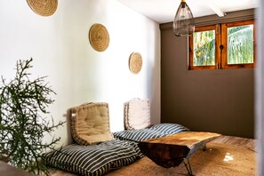 Un rincón acogedor con una mesa de madera, cojines a rayas y adornos de pared tejidos.