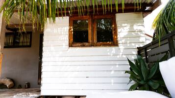 Una casa di legno bianca con una finestra e una porta, circondata da piante.