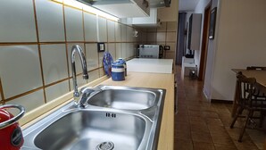 Una cucina con lavello in acciaio inossidabile, bollitore rosso e forno a microonde.