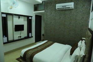 A hotel room with a bed, a television, an air conditioner, and a patterned wall. - The Mirage Palace Hotel (Kisumu)