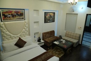 A hotel room with a large bed, a sofa, a coffee table, and two paintings on the wall. - The Mirage Palace Hotel (Kisumu)