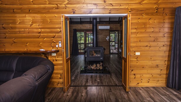 Ein rustikales Blockhaus-Interieur mit einer Couch, einem Kamin und einer Tür zu einem weiteren Raum.