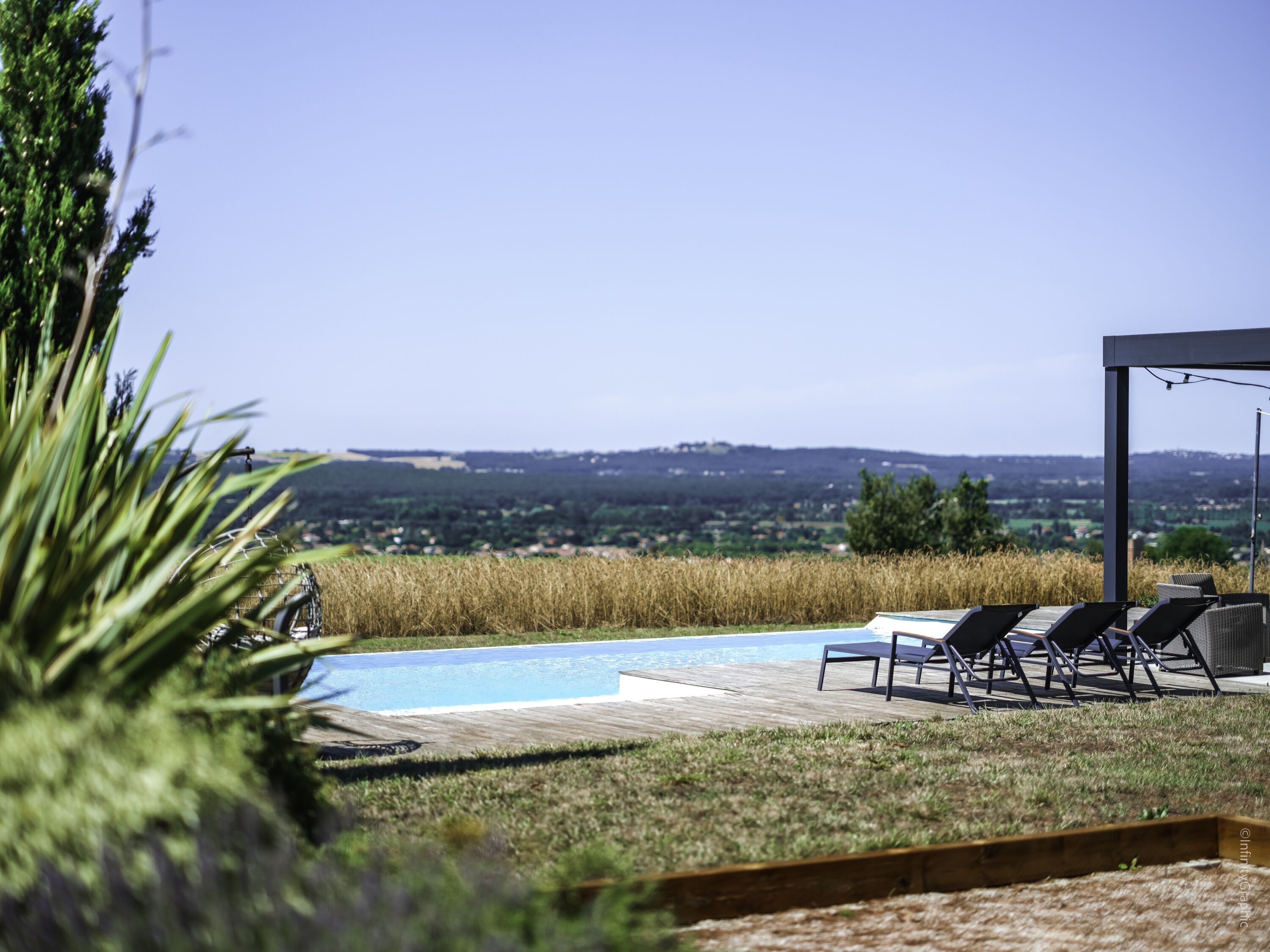 A pool area with lounge chairs and a view of a distant landscape.