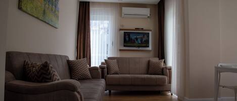 A living room with two sofas, a TV, and a painting on the wall.