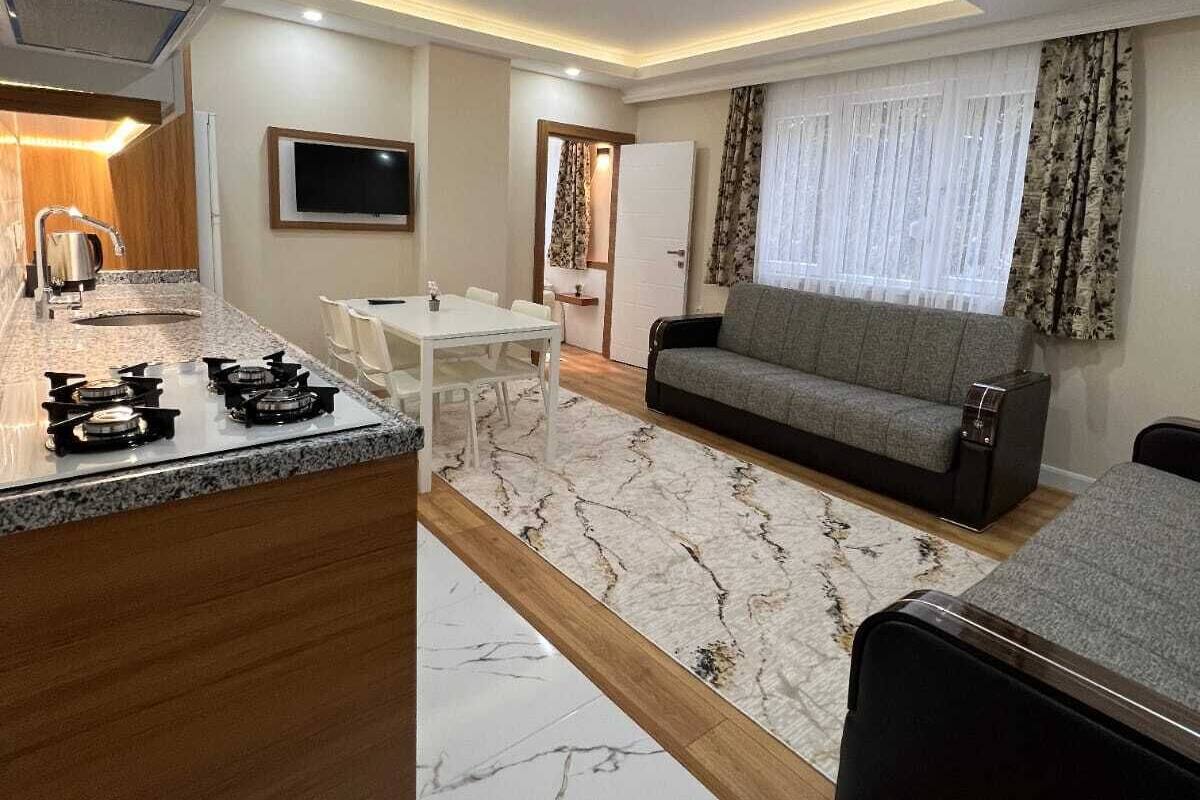 A modern kitchen with a marble countertop and a dining area with a white table and chairs.
