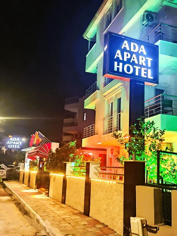 Un edificio con un cartel que dice 'ADA APART HOTEL' de noche.