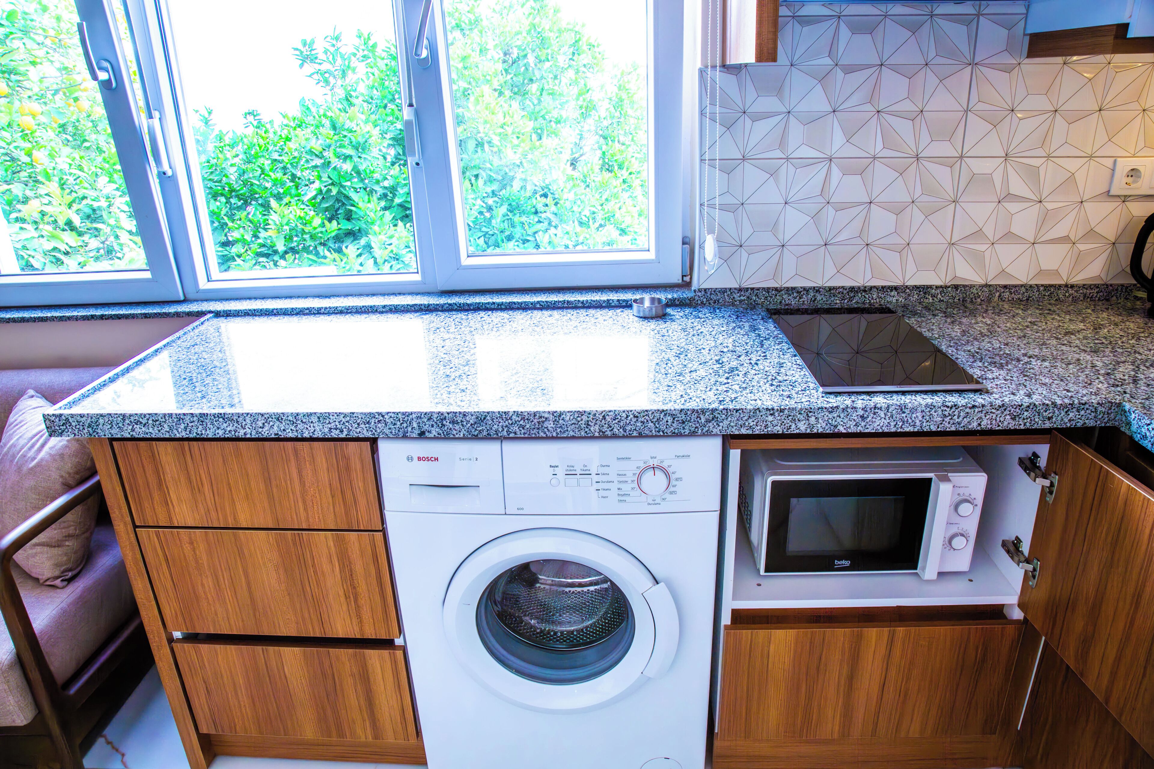 Cocina compacta con lavadora, microondas y encimera de granito.