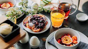 A breakfast setting with a variety of dishes including a berry compote, a glass of orange juice, and a cup of tea.