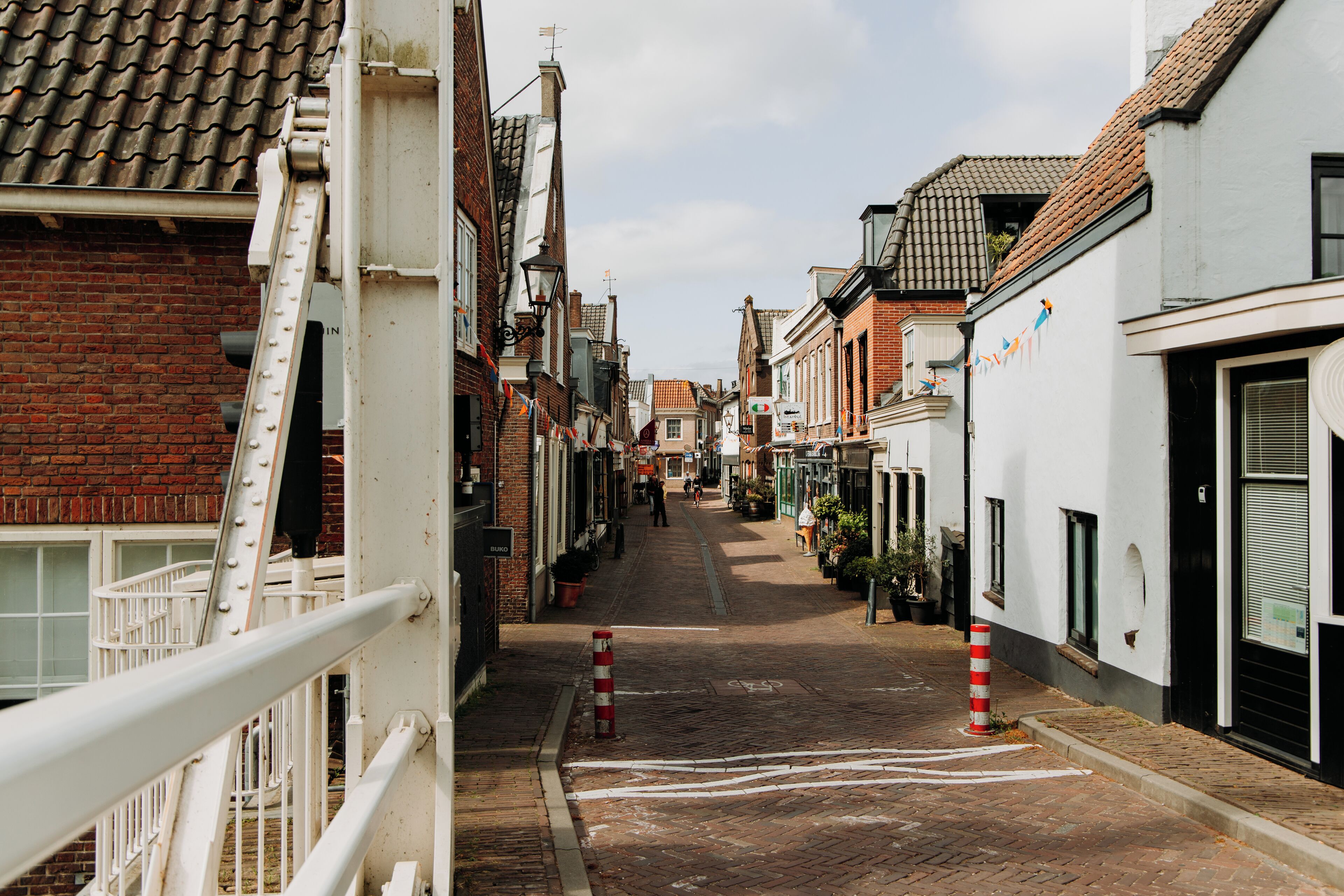 A narrow street lined with traditional buildings, some with visible shop fronts and others with closed shutters.