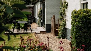 Una casa blanca con un patio jardín, una mesa de madera y sillas.