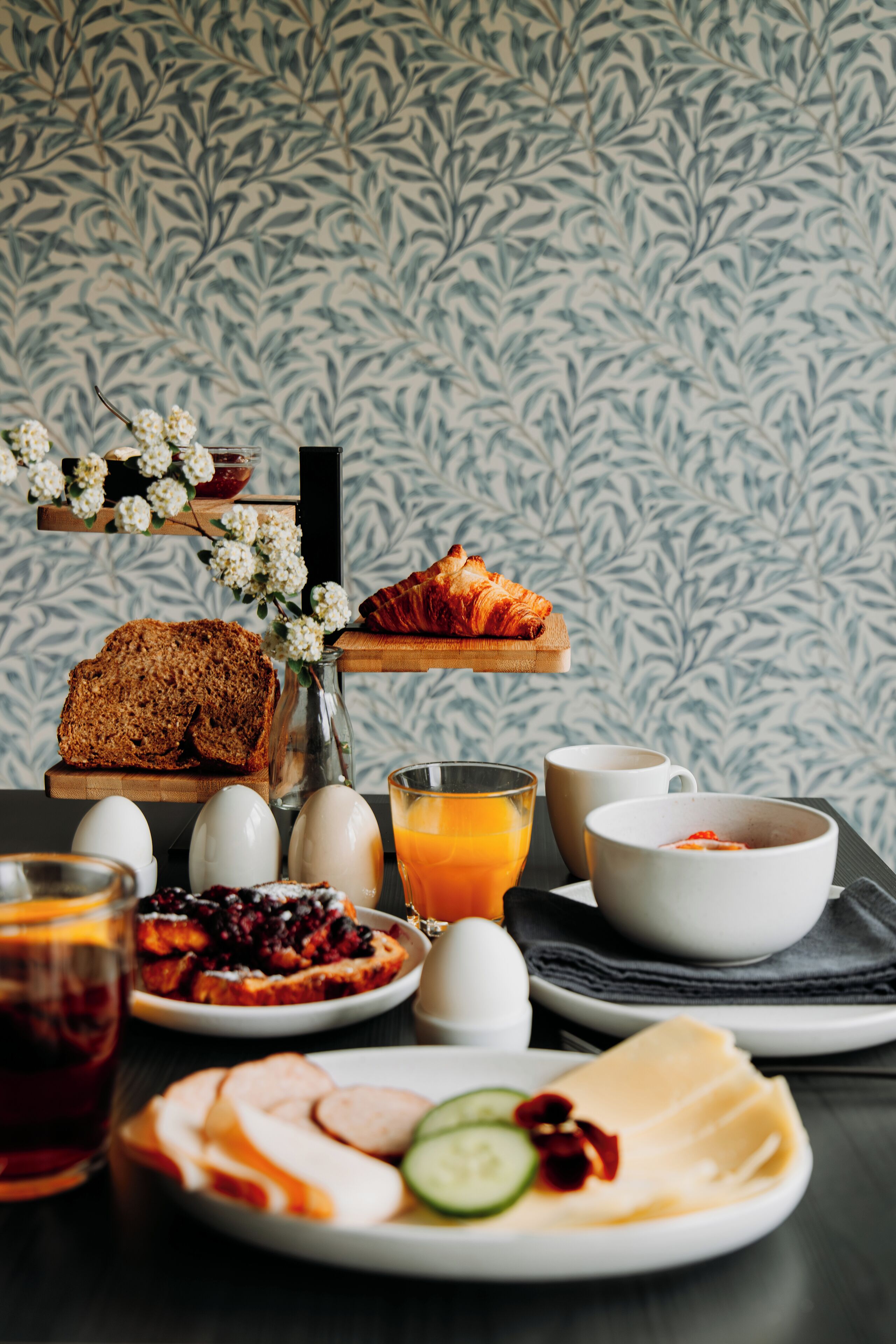 Une table de petit-déjeuner avec du pain, des œufs, du jus et divers fruits.