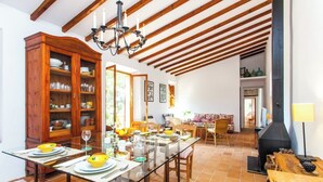 Un comedor espacioso con una mesa de vidrio, sillas de madera y un gran armario de madera lleno de vajilla.