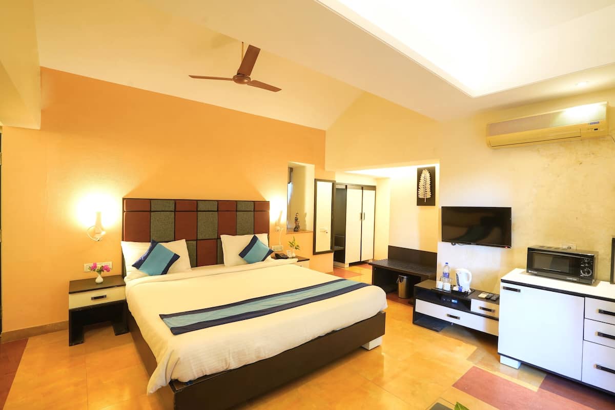 A hotel room with a large bed, a flat-screen TV, a microwave, and a ceiling fan.