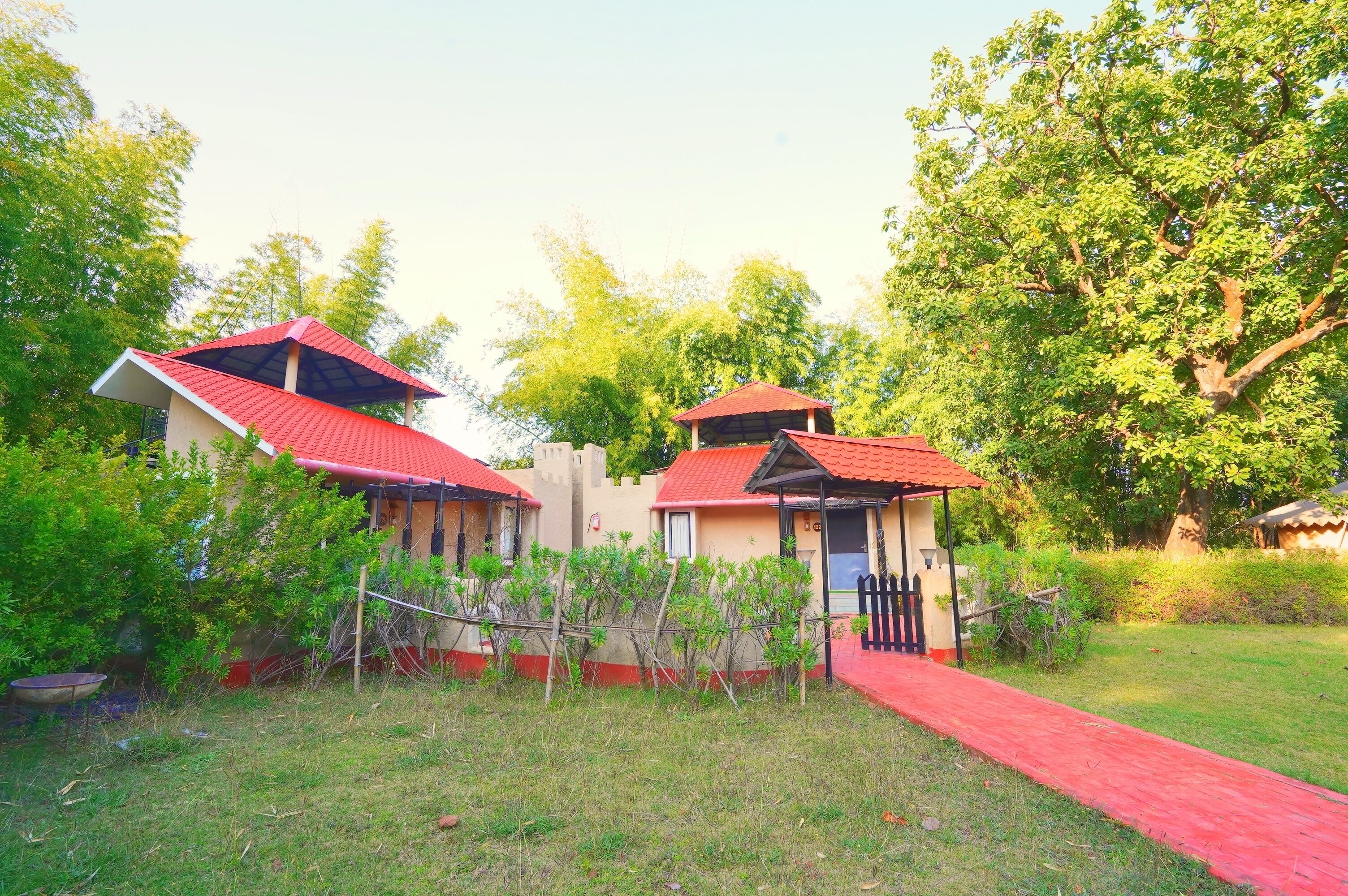 A row of small, single-story buildings with red roofs and a red pathway leading to them.