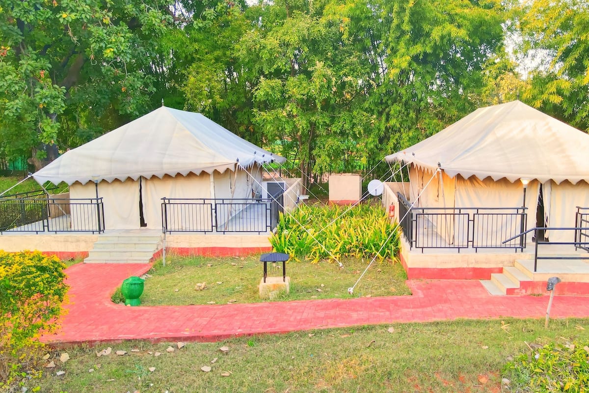 Two white tents with black railings, each with a small staircase leading to a door.