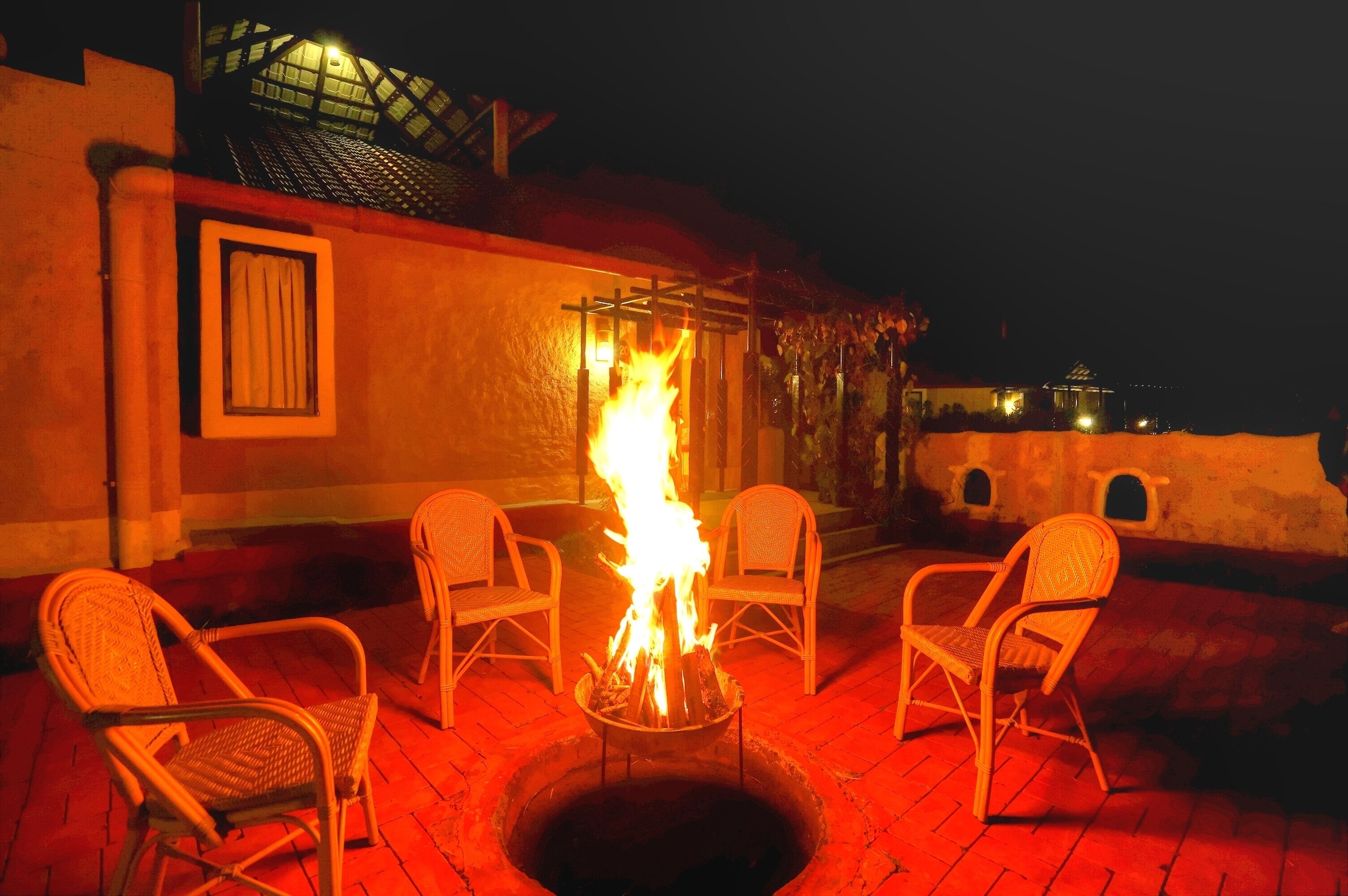 A fire pit with chairs around it on a patio at night.