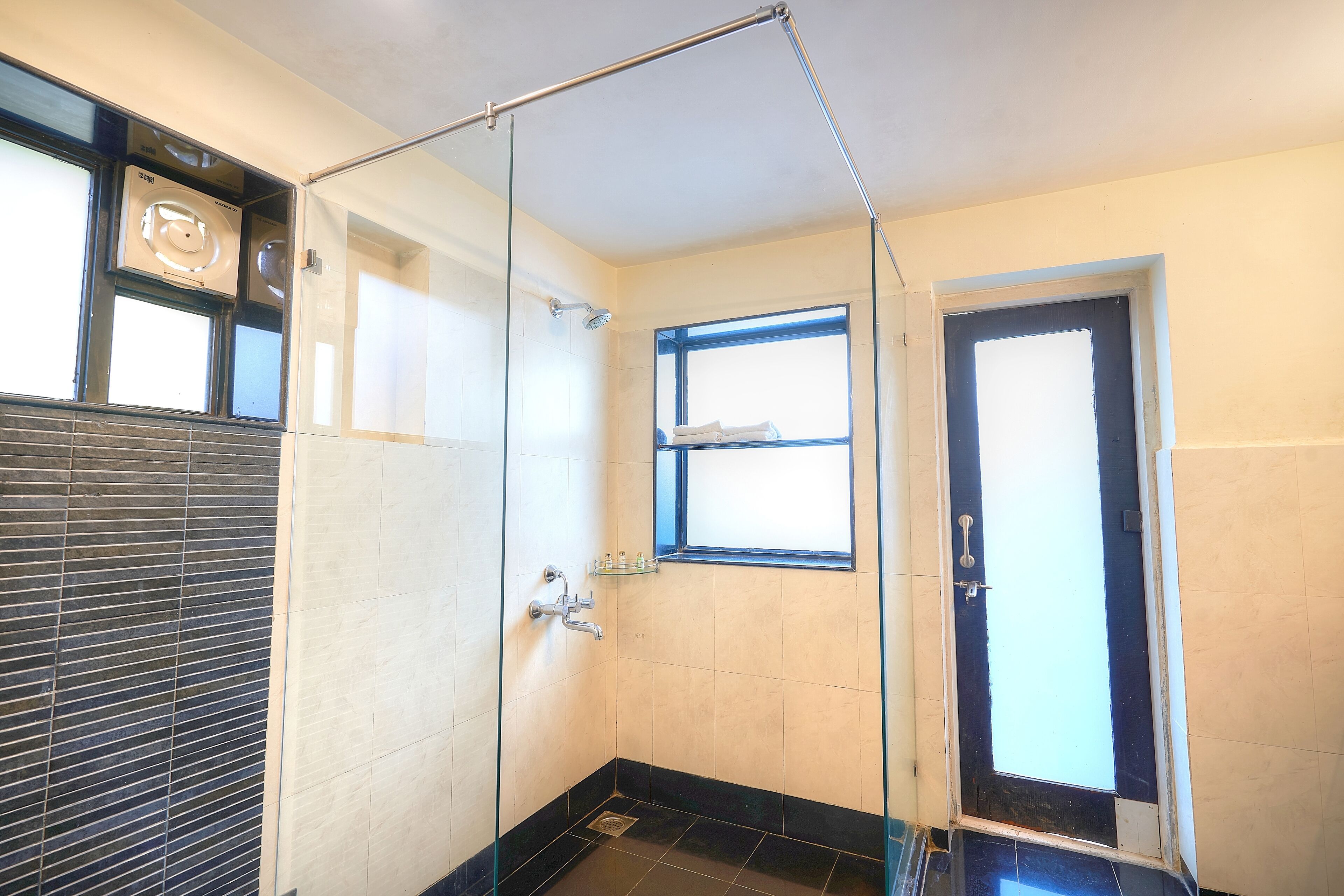Ein modernes Badezimmer mit Duschkabine aus Glas, einem Fenster und einer Tür.