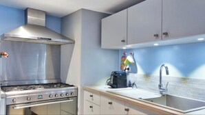 A modern kitchen with a stainless steel stove, a coffee maker, and a sink.