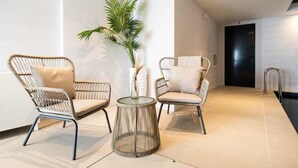 Un interior moderno con dos sillones de mimbre, una mesa de vidrio y una planta en maceta.