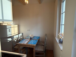 A dining area with a table, chairs, a window, and a cabinet. - Double room 1 with two single beds - Präkel vacation room (Insel Hiddensee)