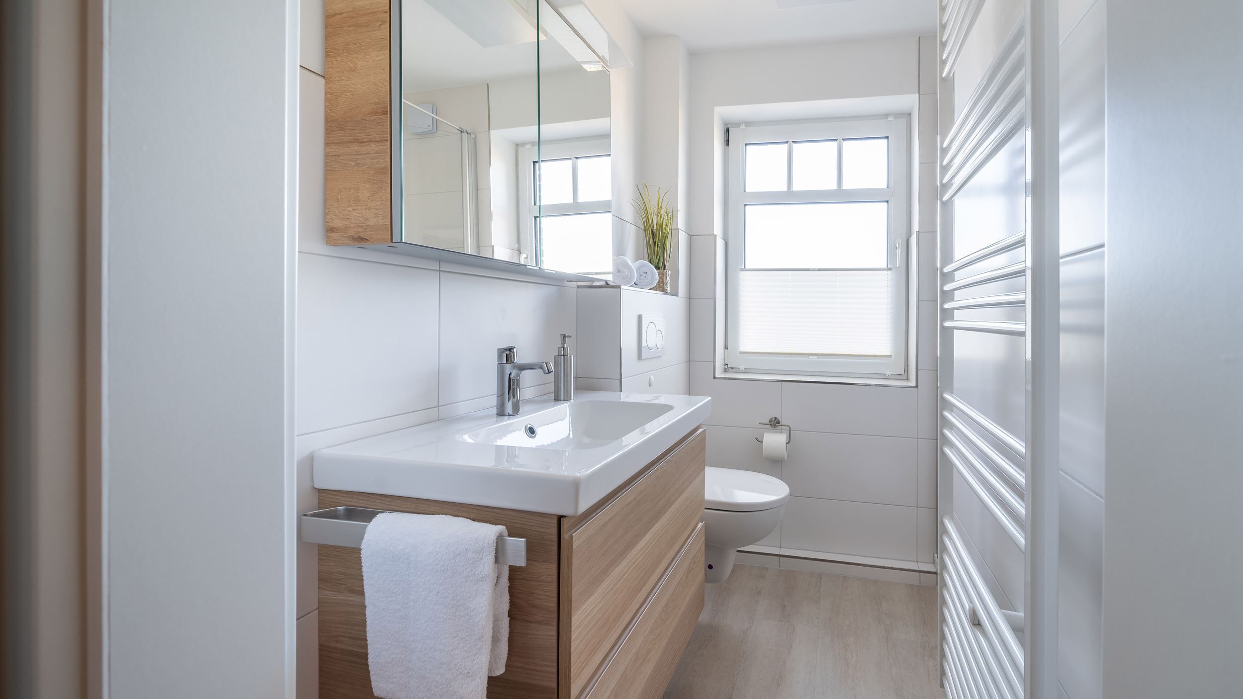A modern bathroom with a white sink, vanity, and toilet.
