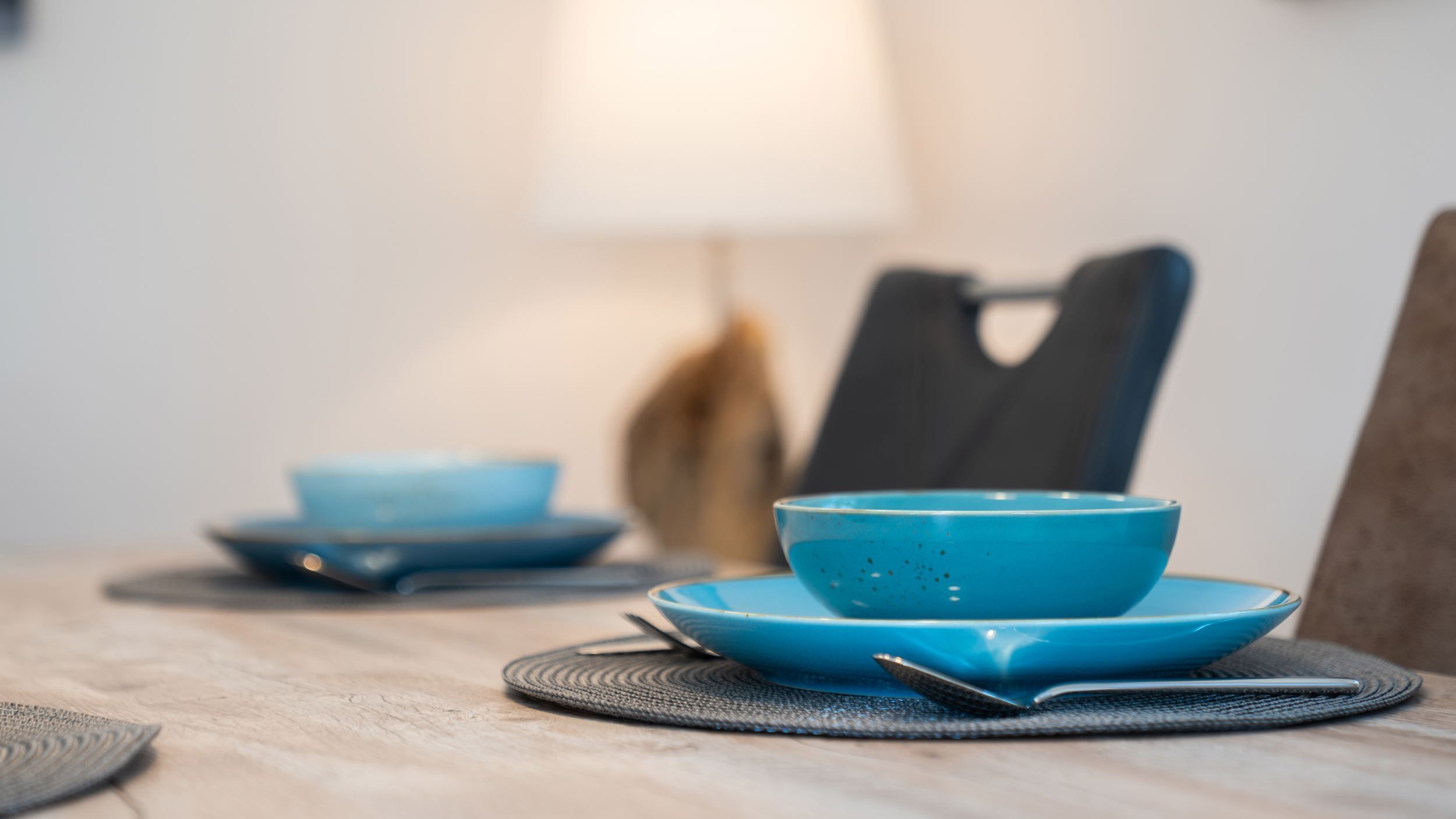 Une table à manger avec un bol et une soucoupe bleus, une cuillère et un set de table.