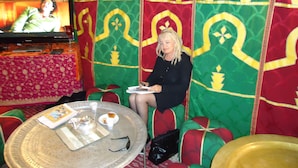 A room with a television, a round table with a tray, and a patterned wall.