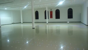 A spacious, well-lit interior with a polished floor, white walls, and a series of windows with arched tops.