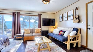 A cozy living room with a sofa, a wooden coffee table, and a TV mounted on the wall. - Cabin Compound | Lake + Alpine Lookout | Fast Wifi (Twin Lakes)