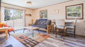 A cozy living room with a sofa, a wooden coffee table, a rug, and a dining area with chairs and a table. - Cabin Compound | Lake + Alpine Lookout | Fast Wifi (Twin Lakes)