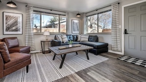 A modern living room with a leather sofa, a wooden coffee table, and a patterned rug.