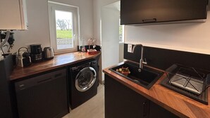 Une cuisine compacte équipée d’un lave-linge, d’une machine à café et d’un évier.