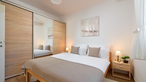 A bedroom with a large bed, a bedside table with a lamp, a small plant, and a painting on the wall. - Sun Spalato Villa Cikas (Murter-Kornati)