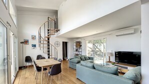 Un salon moderne doté d’un escalier en colimaçon, d’un coin repas et d’un grand téléviseur.