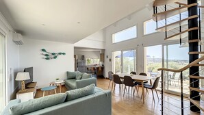 Un vaste espace de vie comprenant un escalier moderne, une table à manger et un canapé.
