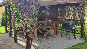 A covered outdoor seating area with a table and chairs, a grill, and a pergola with climbing plants. - 4 bedroom amazing home in Parzensko (Parzensko)