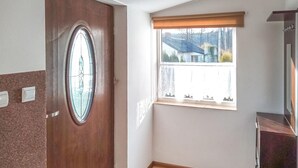 A room with a wooden door, a window with a view of a house, and a small wooden cabinet. - 4 bedroom amazing home in Parzensko (Parzensko)