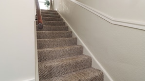 Un escalier recouvert de moquette, doté d’une rampe, menant à l’étage supérieur.