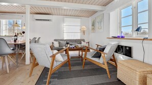 A living room with a sofa, chairs, a dining table, and a fireplace. - Lovely home in Svaneke with WiFi (Svaneke)