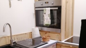 A compact kitchen with wooden cabinetry, a built-in microwave, and a stainless steel sink.