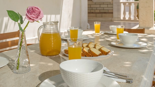 A table set for breakfast with a pitcher of orange juice, bowls, and plates of toast. - Villa Serenity (Kropia)