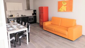 Ein kompakter Wohnbereich mit Essplatz, Küchenzeile und einer Couch.